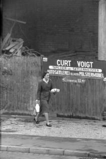 ARH NL Dierssen 1407/0009, Eine Frau auf einem Gehweg vor einer Mauer mit Reklame, Hannover, 1960