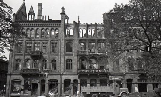 ARH NL Koberg 9426, Zerstörte Geschäfte, unter anderem "Foto Möhlen", "Erich Möller Rad" und "H. Döpke Gaststätte", (Zwangs?)Arbeiter verräumen Trümmer, vermutlich Georgstraße?, Hannover, 1943