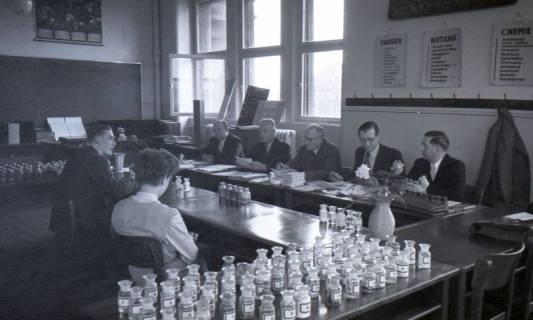 ARH NL Koberg 9672, Sechs Männer in Anzügen sitzen zwei jungen Personen in einem Lehrraum gegenüber, eventuell eine Prüfung, Hannover?, 1953