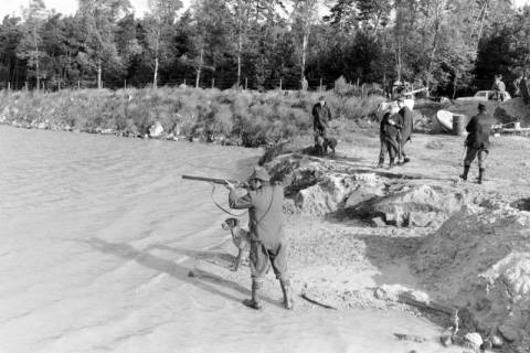 ARH NL Mellin 01-006/0013, Jäger mit angelegtem Gewehr und Jagdhund am See, ohne Datum
