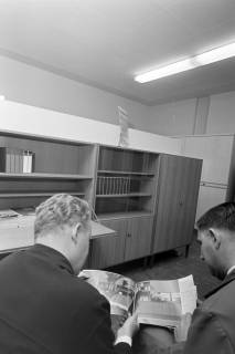 ARH NL Mellin 01-129/0003, Zwei Männer im Möbelgeschäft "3 K-Möbel" mit Blick in den Katalog, nach 1964