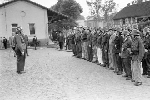 ARH NL Mellin 01-174/0008, Aufgereihte Feuerwehrleute (vermutlich bei einer Übung) am Bahnhof, Burgdorf, um 1950