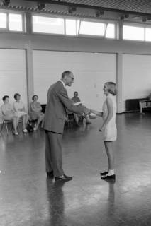 ARH NL Mellin 01-196/0015, Ehrung eines jungen Mädchens durch Oberstudiendirektor Johann-Georg Krogel in der Sporthalle des Gymnasiums, Burgdorf, um 1970