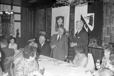 ARH NL Mellin 02-038/0006, Personen bei einer politischen(?) Veranstaltung, im Hintergrund rechts das Wappen des Landkreises Burgdorf, ohne Datum