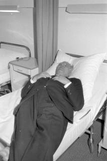 ARH NL Mellin 02-067/0004, Mann auf einem Bett liegend bei der Besichtigung eines Krankenhauszimmers(?), ohne Datum