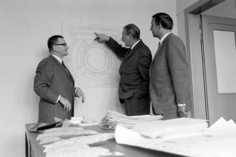 ARH NL Mellin 02-077/0006, Drei Männer vor einem Plan des Kuppelsaals des Hannover Congress Centrums (HCC) stehend, ohne Datum