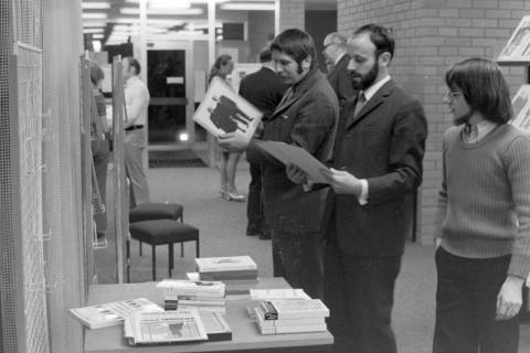 ARH NL Mellin 02-089/0017, Drei Männer vor einem Büchertisch, ohne Datum