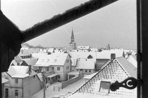 ARH NL Mellin 02-199/0010, Blick aus einem Fenster auf die verschneiten umliegenden Häuser und die Pankratiuskirche, Burgdorf, um 1970