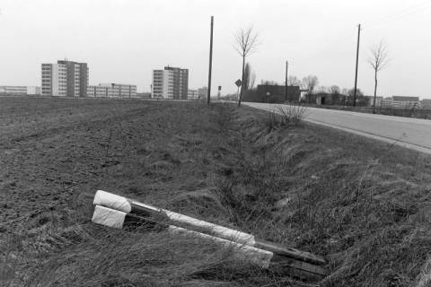 ARH NL Mellin 02-200/0008, Blick über zwei am Straßenrand der Immenser Landstraße liegende Leitpfosten auf den Ortseingang, Burgdorf, um 1970