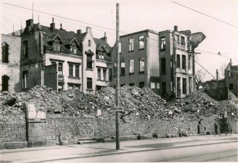 ARH Slg. Mütze 013, Trümmer hinter einer Trockenmauer und Holzmast für die Befestigung der Oberleitung der Straßenbahn in der Königstraße, Hannover, zwischen 1943/1949