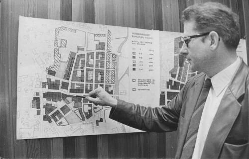ARH Slg. Bartling 209, Stadtdirektor Felix Rohde zeigt auf eine an der Wandpaneele aufgehängte Karte mit dem räumlichen Konzept zum Stadtbild von Neustadt am Rübenberge, 1973