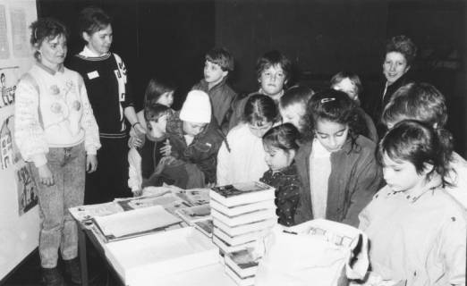 ARH Slg. Bartling 383, Gruppe von Kindern mit Lehrerin ? (rechts) vor einem Büchertisch in der Stadtbücherei, um 1970