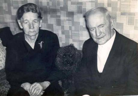 ARH Slg. Bartling 1373, Ehepaar Heinrich und N. N. Delaminsky auf dem Sofa im Wohnzimmer sitzend, zwischen ihnen ein schwarzer Pudel, Mandelsloh, um 1975