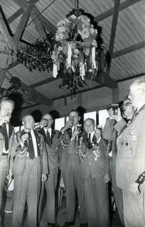 ARH Slg. Bartling 1498, Erntefest in einer Scheune, eine Gruppe von Männern in Schützenuniform unter der Erntekrone beim Anstoßen, Bevensen, 1974