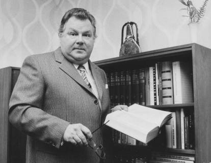 ARH Slg. Bartling 1649, Landrat des Landkreises Neustadt a. Rbge. Alfred Semsroth (SPD, 1972-1974) mit aufgeschlagenem Buch in der linken und Brille in der rechten Hand, Neustadt a. Rbge., um 1973