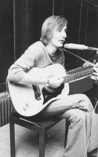 ARH Slg. Bartling 1815, Chansonier Jürgen Albrecht sitzend mit Gitarre und Mikrofon beim Musikvortrag, Aufnahme von schräg links, Neustadt a. Rbge., 1973