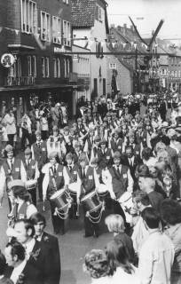 ARH Slg. Bartling 1819, Fanfarenzug des Neustädter DRK beim Marsch durch die mit Fähnchen geschmückte Marktstraße, Blick von der Rathaustreppe, Neustadt a. Rbge., um 1975