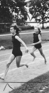 ARH Slg. Bartling 1943, Zwei junge Sprinterinnen auf der Laufbahn des TSV-Sportplatzes beim Stabwechsel, Blick vom Innenrand, Neustadt a. Rbge., 1974