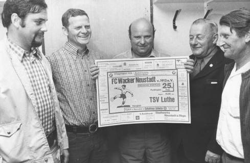 ARH Slg. Bartling 1991, Vier Sportsfreunde präsentieren das Plakat mit der Ankündigung der Fußball-Partie zwischen dem FC Wacker Neustadt und dem TSV Luthe, 1974