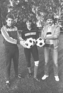 ARH Slg. Bartling 2017, Gruppenporträt von drei jungen Spielern in Sportkleidung mit Fußbällen in den zur Mitte ausgestreckten Händen auf dem TSV-Sportplatz, Neustadt a. Rbge., um 1975