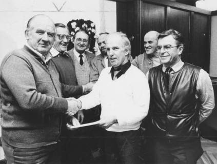 ARH Slg. Bartling 2023, Der Vorsitzende des Versehrtensportvereins Kurt Dahlke (l.) überreicht dem N. N. eine Urkunde, im Hintergrund mehrere Vereinskollegen, um 1975