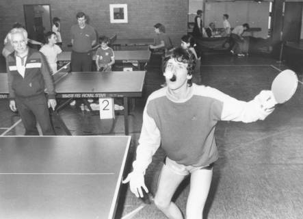 ARH Slg. Bartling 2031, Junge Tischtennisspieler beim Training an mehreren Tischen in einer Turnhalle, im Vordergrund ein Spieler beim Aufschlag, neben den Tischen die Trainer, um 1975