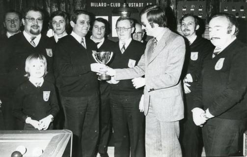 ARH Slg. Bartling 2238, Überreichung eines Pokals an Klaus Paschke, umstanden von zahlreichen Männern, durch Rolf Hantelmann von der Sparkasse Neustadt im Billardstudio des Billard-Clubs Neustadt e. V., Neustadt a. Rbge., 1974