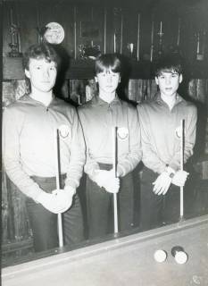 ARH Slg. Bartling 2242, Drei junge Billardspieler im Billardstudio aufrecht hinter einem Billardtisch stehend und den Queue senkrecht vor dem Körper haltend, Neustadt a. Rbge., um 1971