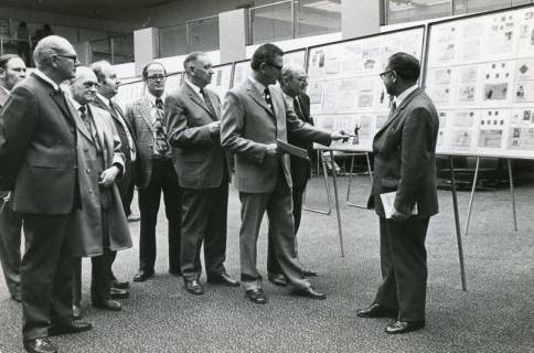 ARH Slg. Bartling 2257, Der Club-Vorsitzende Heinrich Schöneberg (Bildmitte) erklärt die Exponate einer Briefmarkenausstellung in der Schalterhalle der Kreissparkasse, Neustadt a. Rbge., 1973