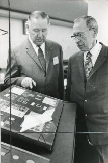 ARH Slg. Bartling 2258, Ein älterer Herr lässt sich von Emil Block (l.) die Exponate auf der Tafel einer Briefmarkenausstellung in der Schalterhalle der Kreissparkasse erklären, Neustadt a. Rbge., 1973