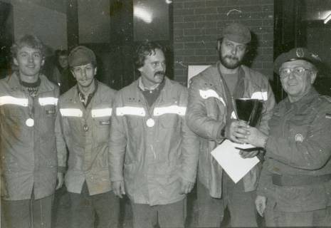 ARH Slg. Bartling 2285, Oberfeldwebel in Arbeitsuniform (r.) überreicht einer Gruppe von vier Männern in Zivil mit Uniformjacke einen Pokal, Neustadt a. Rbge., um 1970