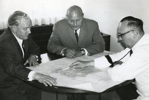 ARH Slg. Bartling 2558, Landrat Friedrich Meyer (v. l.), Stadtdirektor Otto Hergt, Dr. Hermann Pfanz, Kali-Chemie, um einen Tisch sitzend und einen Lageplan der Firma Kali-Chemie Pharma studierend, 1970
