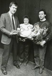 ARH Slg. Bartling 2794, Sparkassenangestellter Rainer Weihrauch (l.) überreicht Frau N. N. und Joachim Tiesler (Sport Tiesler) einen Blumenstrauß in Folie und ein Heft, Neustadt a. Rbge., um 1975