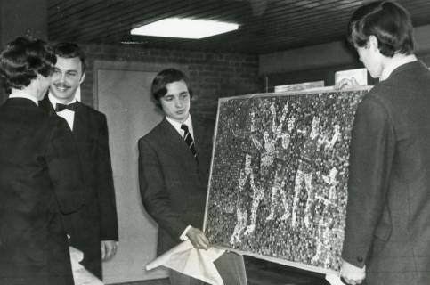 ARH Slg. Bartling 2989, Hans-Böckler-Schule, Zwei festlich gekleidete Schüler und ihr Lehrer Florian Düe präsentieren einer Dame ein gerahmtes Mosaikbild, Neustadt a. Rbge., 1969