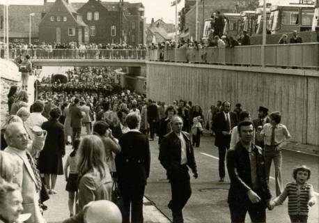 ARH Slg. Bartling 3092, Einweihung der Eisenbahn-Unterführung und des Zentralen Omnibusbahnhofs: Zahlreiche Besucher auf der Landwehr-Straße, Blick von Westen auf die Eisenbahnbrücke, rechts oben mehrere Busse im Depot, Neustadt a. Rbge., 1975