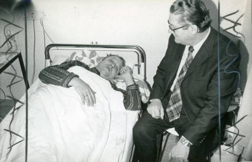 ARH Slg. Bartling 3120, Patient Helmut Greulich, Niedersächsischer Minister für Wirtschaft und Verkehr im Krankenbett liegend, daneben der Niedersächsische Minister des Innern Richard Lehners auf einem Stuhl am Bett sitzend, Neustadt a. Rbge., 1974