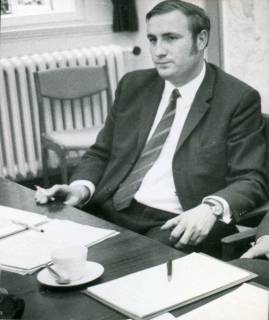 ARH Slg. Bartling 3157, Kreiskrankenhaus (später: KRH Klinikum Neustadt a. Rbge.), Lindenstraße 75: Friedrich Schmidt (später: Manhal), Verwaltungsdirektor, Porträt hinter einem Schreibtisch sitzend, Neustadt a. Rbge., um 1975