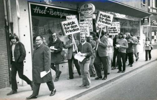 ARH Slg. Bartling 3388, Mitglieder der Neustädter SPD marschieren demonstrierend mit Plakaten (Aufschrift: "Politik für den Frieden", "Gegen die Verschleierungspolitik der CDU") auf der Marktstraße vor dem Hutgeschäft Bergmann, Neustadt a. Rbge., 1972