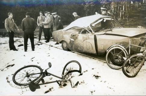 ARH Slg. Bartling 3396, Auf schnee- und eisglatter Straße verunglücktes Auto (Ford 12m), davor zwei dämolierte Fahrräder im Schnee, dahinter mehrere Zivilisten samt Soldaten und Polizisten stehend und diskutierend, 1971