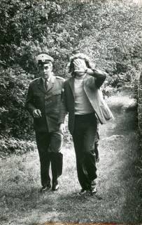 ARH Slg. Bartling 3424, Abführung eines festgenommenen Mannes (der mit seiner linken Hand sein Gesicht verdeckt) durch einen Polizisten mit gezogener Pistole auf einem Waldweg, Bordenau, 1971