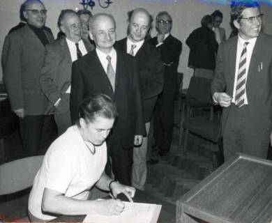ARH Slg. Bartling 3461, Versammlung von einigen Männern und Frau Wiebking, die sich in die Anwesenheitsliste einträgt, Neustadt a. Rbge., 1971