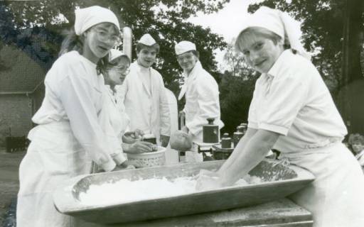 ARH Slg. Bartling 3572, Auszubildende in weißem Kittel und mit Kopftuch bzw. Schiffchen am Tisch im Freien beim Kneten von Teig, Neustadt a. Rbge., um 1980