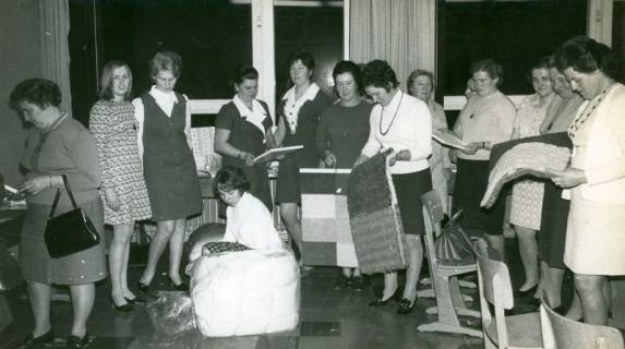 ARH Slg. Bartling 3584, Begutachtung der Handarbeiten (Fußmatten u. a.) von Schülerinnen der Landwirtschaftlichen Berufsschule durch zahlreiche ältere Frauen, Neustadt a. Rbge., um 1970
