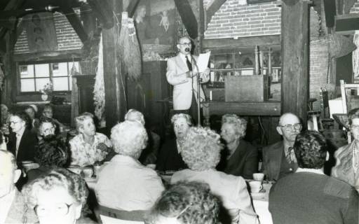 ARH Slg. Bartling 3701, Zahlreiche ältere Leute in der Zehntscheune, Blick über die Kaffeetafel auf einen Redner am Mikrofon, Mandelsloh, 1986