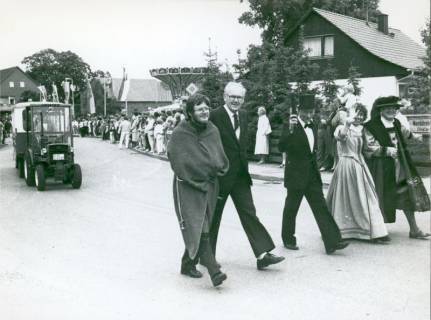 ARH Slg. Bartling 3706, Umzug anläßlich der 1000-Jahr-Feier von Mandelsloh, Fußgruppe mit modernen und mit "historischen" Kleidern, am Straßenrand zahlreiche Zuschauer und ein Kettenkarussell, Mandelsloh, 1985