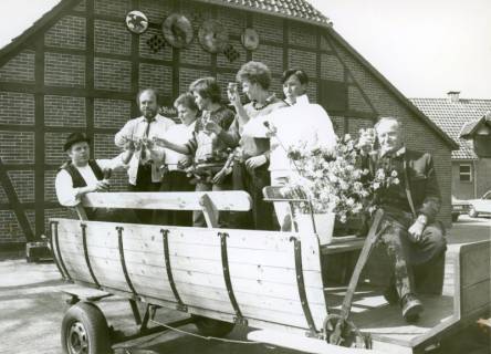 ARH Slg. Bartling 3707, Umzug am Erntefest (?), Gruppe von Personen auf einem renovierten Pferdewagen vor der Fachwerk-Giebelwand eines Bauernhauses, Mandelsloh, um 1985