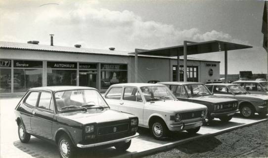 ARH Slg. Bartling 3870, FIAT-Autohaus Mineif, Blick über die nebeneinander abgestellten Verkaufsangebote auf die Gebäudefront, Bordenau, 1972