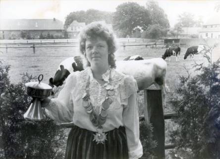 ARH Slg. Bartling 3958, Einzelporträt der Schützenkönigin mit Pokal in der Rechten und Königskette auf der Brust vor einer Weide mit Rindern, Frontalansicht, Brase, 1983
