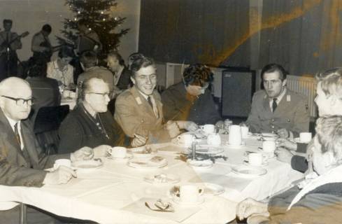 ARH Slg. Bartling 4384, Vorweihnachtliche Feier der Soldaten mit älteren Leuten als Gäste, Blick über den Kaffeetisch auf den erleuchteten Weihnachtsbaum und eine Musikband, Luttmersen, 1968