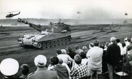 ARH Slg. Bartling 4388, Tag der offenen Tür, Vorführung einer Gefechtsübung mit Panzern und Hubschraubern im Gelände, Blick über die zahlreichen am Rande befindlichen Zuschauer auf einen vorbeirollenden Panzer und die übrige Szene, Luttmersen, 1971